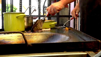 Arm of a man who is cooking meat in a traditional kitchen