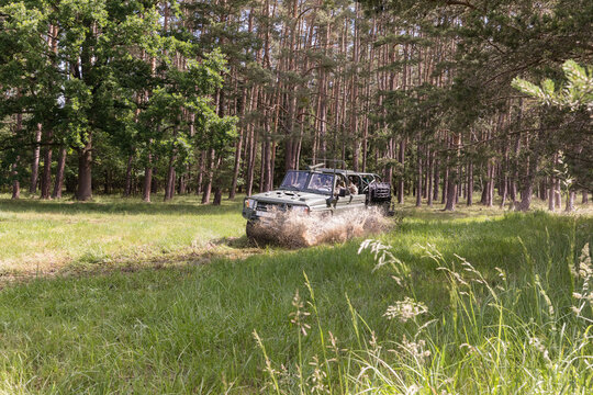A military all-terrain vehicle travels through the countryside through puddles of mud.