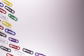 Colored paper clips for product advertising. Metal office clips attach, on a light background. Stationery fix tool for page, card. The equipment for documentation.