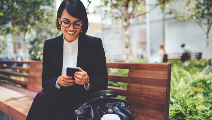 Cheerful businesswoman in elegant black suit feeling happy from received email with good news from...