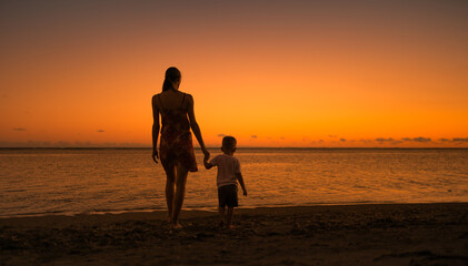 Mother and child walking down a beautiful beach holding hands. Parenting and childhood concepts. 