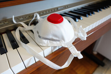 White safety breathing mask with red filter on piano close up. Medicine anti virus mask left on...