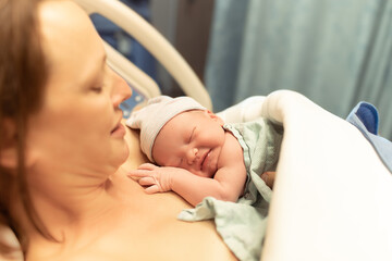Mother and her newborn baby in hospital bed. Giving birth, and new life concept. 