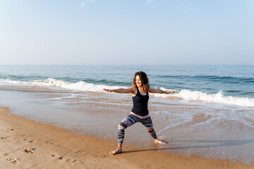 a young girl of European appearance does yoga on the beach early in the morning, practicing asana on the beach in India