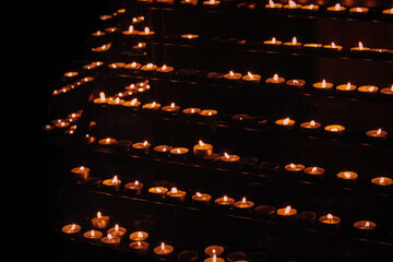  Many Lit Candles Stand In Rows Against A Dark Background.