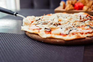 Pizza with sausages, mushrooms and mozzarella. Top view. A spatula that lifts a slice of pizza. Free space for your text