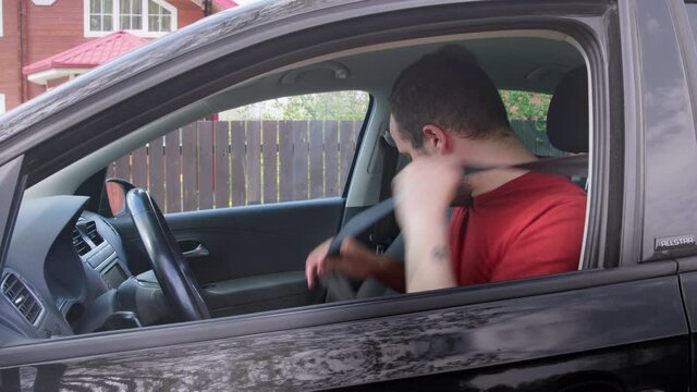 Bearded Caucasian Male driver preparing to drive a car. Rearview mirror adjustment. Fastening seat belt. The car pulls away.Safe driving concept.