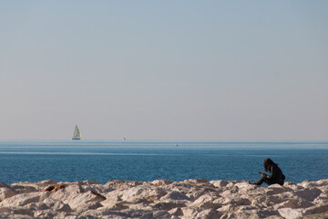 femme assise au bord de la mer avec son téléphone