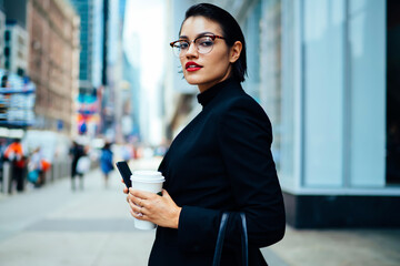 Half length portrait of confident proud ceo expert dressed in elegant apparel looking at camera while standing on Manhattan street during work break for coffee, attractive businesswoman outdoors
