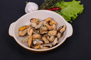 Pickled mussels in the bowl served pepper, garlic and salad