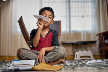 Boy playing handmade paper airplane at home quarantine