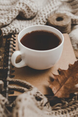 Sweaters and cup of tea with notebook, candle and knitting clothes. Cozy autumn or winter concept.