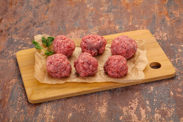 Raw meatball over wooden background