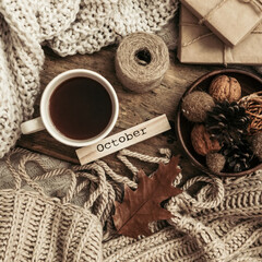 Sweaters and cup of tea with notebook, candle and knitting clothes. Cozy autumn or winter concept.