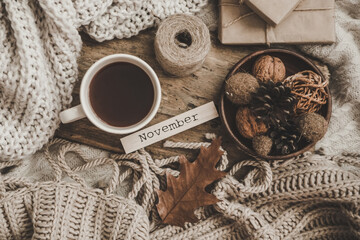 Sweaters and cup of tea with notebook, candle and knitting clothes. Cozy autumn or winter concept.