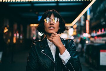 Young trendy dressed hipster in eyewear with night city light reflection fascinated with beautiful...