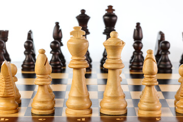 Wooden chess. Chess pieces arranged on a chessboard. Isolated on white background. Close-up