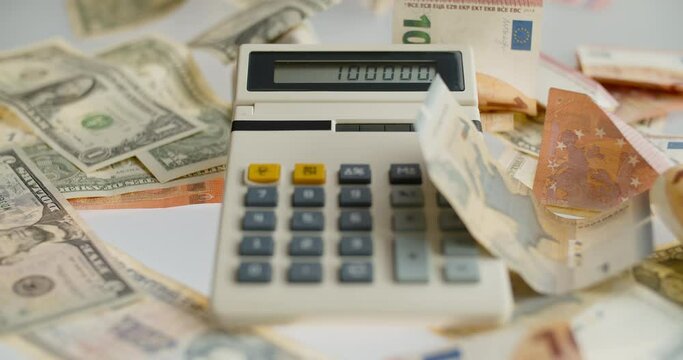 Calculator and falling paper currency. View of an old calculator and international paper currency. Counted summ on calculators screen. Money signs. Counting money. Home finances concept.