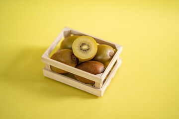 Sun gold kiwi in wooden fruit crate on a yellow background