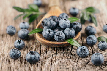 Fresh blueberries in wooden spoon on wood background. Healthy eating concept.
