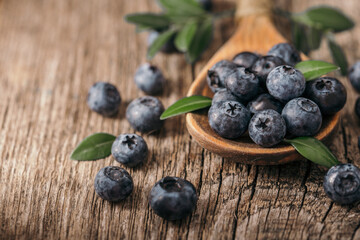 Fresh blueberries in wooden spoon on wood background. Healthy eating concept.