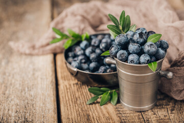 Blueberries in metal dishes on wooden table. Healthy eating and nutrition.