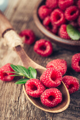 Raspberries in spoon on wooden table. Healthy eating and nutrition.