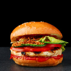 tasty burger with chicken on dark isolated background. Homemade hamburger or burger with fresh vegetables and cheese