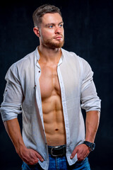 Super sexy man with tan abs and chest. Athletic man with unbuttoned white shirt on dark background....