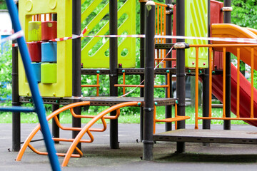 Fototapeta na wymiar The play park of amusement and sports for young children is wrapped in red barrier tape. Outside. Prohibition of outdoor walks, prevention of the coronavirus influenza virus covid-19. europe.