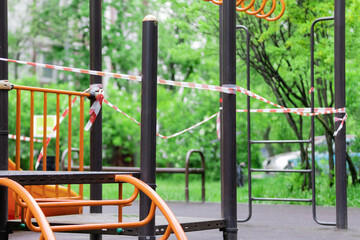 Fototapeta na wymiar The play park of amusement and sports for young children is wrapped in red barrier tape. Outside. Prohibition of outdoor walks, prevention of the covid-19. moscow. selective focus