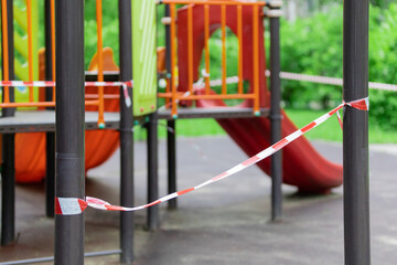 Fototapeta na wymiar The play park of amusement and sports for young children is wrapped in red barrier tape. Prohibition of outdoor walks, prevention of the coronavirus influenza virus covid-19. lockdown. selective focus