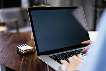 Mockup image of a woman using laptop with blank screen on wooden table
