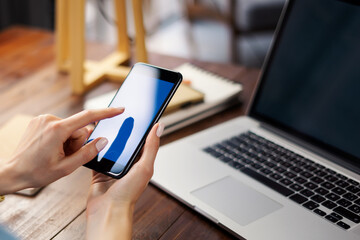Mockup image of a woman using smartphone with blank screen on wooden table