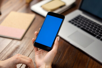 Mockup image of a woman using smartphone with blank screen on wooden table