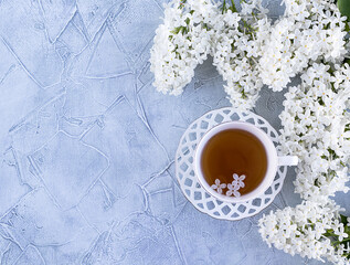 Obraz na płótnie Canvas Blooming white lilac Cup and saucer on a gray background. The concept of good morning. flat lay. copyspase