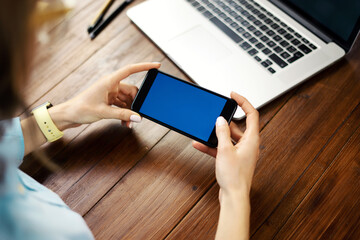 Close up photo of female hands holding smartphone horizontally. Mockup concept with copy space and blank screen