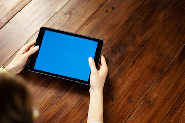 Mockup image of a woman using digital tablet with blank screen on wooden table. Close up photo of female hands holding device horizontally