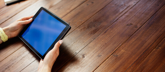 Mockup image of a woman using digital tablet with blank screen on wooden table