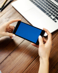 Close up photo of female hands holding smartphone horizontally. Mockup concept with copy space and blank screen