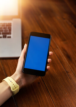 Mockup image of a woman using smartphone with blank screen on wooden table.