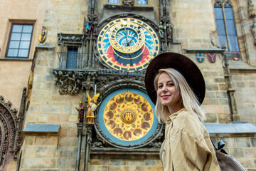 Blonde girl with hat and backback near famous clock in Prague, Czech Republic