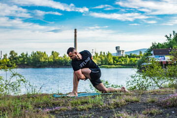 Bearded handsome practices yoga and meditates in the lotus position on the t the backdrop of beautiful nature. International day of yoga.