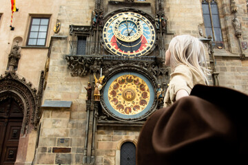 Blonde girl with hat and backback near famous clock in Prague, Czech Republic