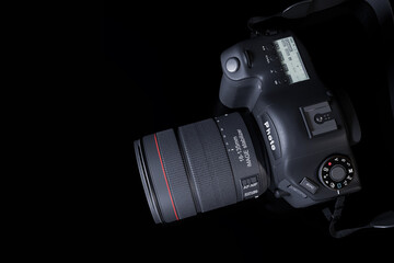 Top view professional digital camera with a zoom lens and a leather strap on a black background with copy space. View from above. Realistic 3d render. Place for advertising text. Reflection at bottom