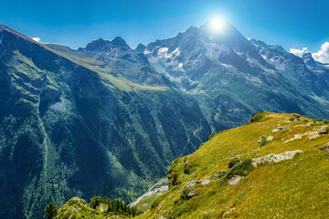 The bright sun hides behind the top of the mountain. The view from the hill. Cloudless sky and natural space. The concept of business thinking, a good idea or message.
