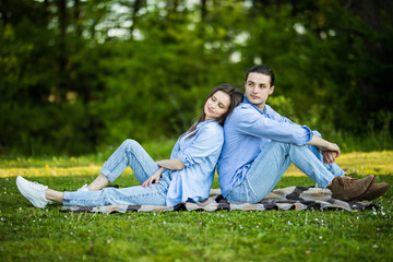 Young Couple sitting in the garden on the blanket back to back and girl is sad