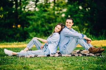 Young in loved couple sitting on the grass in a summer garden