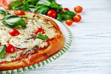 italian pie with tomatoes and cheese and basil on light wooden background closeup. Italian margherita pizza with tomatoes chees and basil leaf