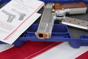 gun or pistol inlaid with wood and gold and bullet holder in a blue box on a american flag background. weapon concept. protection and violence.
